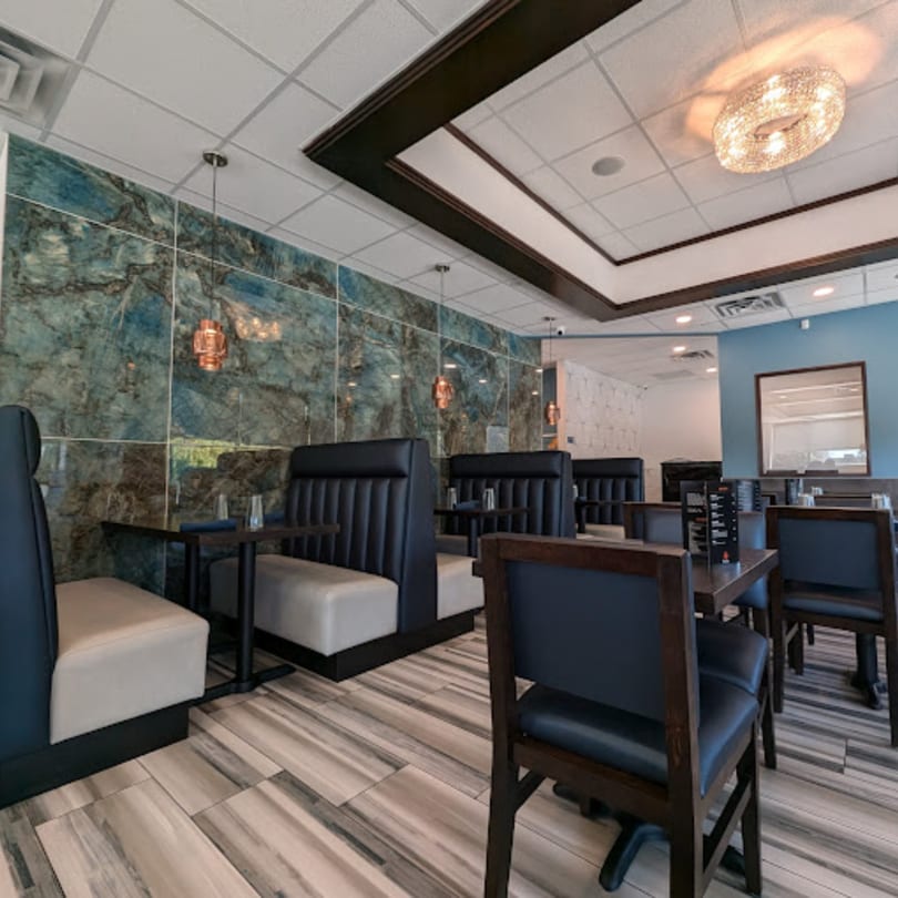 Clay Oven restaurant interior with blue marble walls, black booths, and wooden tables.