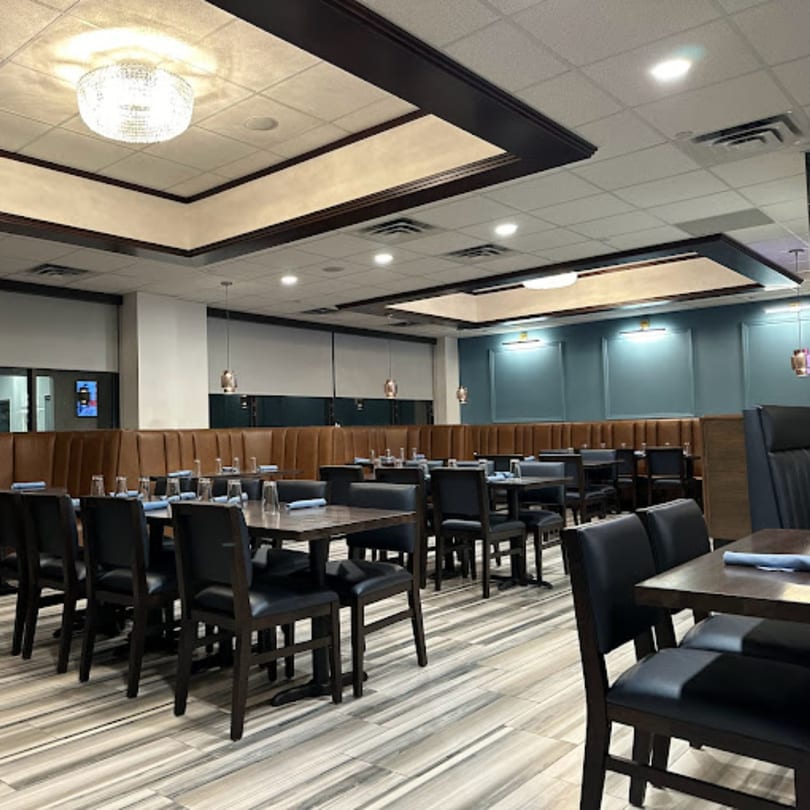Clay Oven's dining room with dark tables, black chairs, brown booths, and blue accent walls.